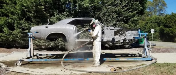 man painting the frame of a car