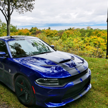 Blue 2018 Dodge Charger SRT Hellcat driving along road with trees changing color