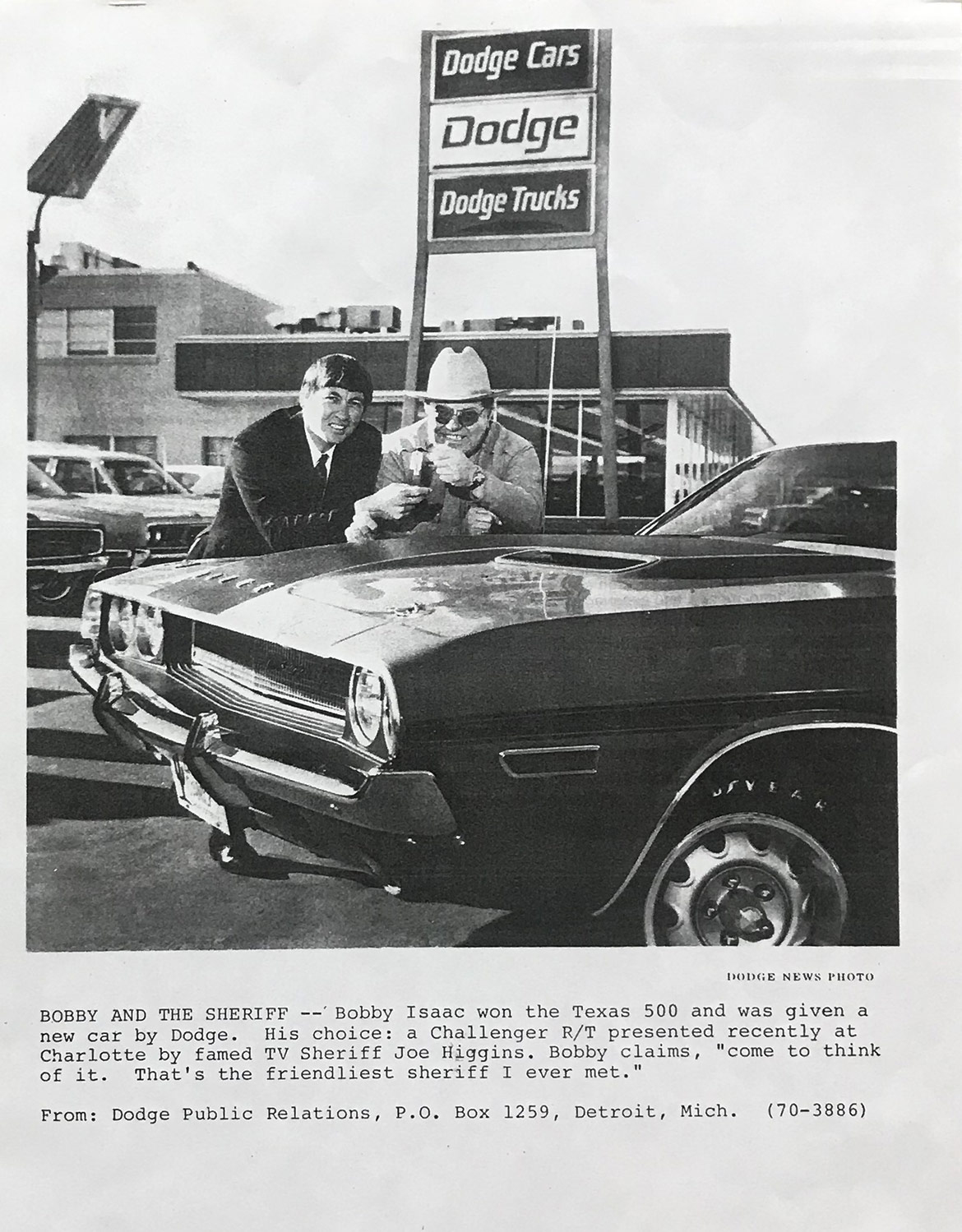 old picture of two men with a car at a dodge dealership