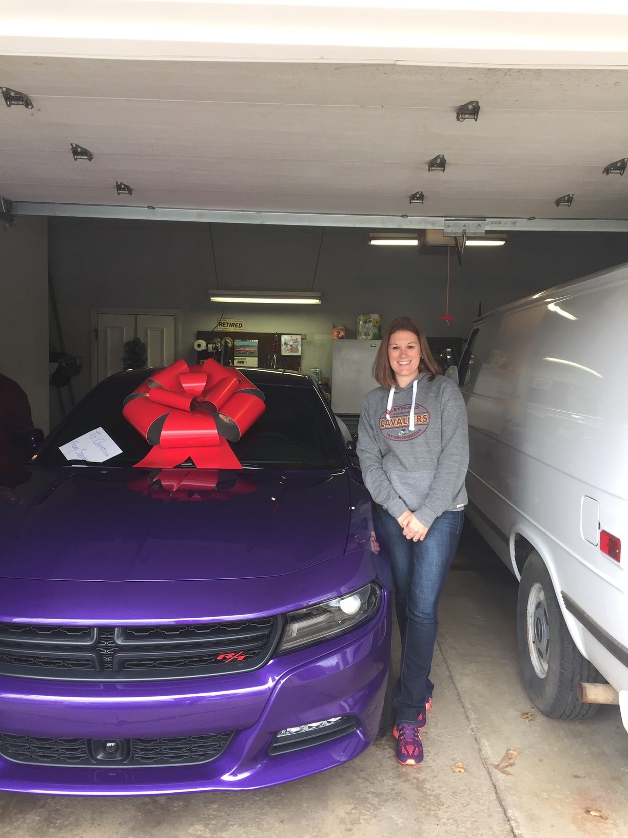 Christina Nash standing by her 2016 Dodge Charger R/T with a big red bow on top.