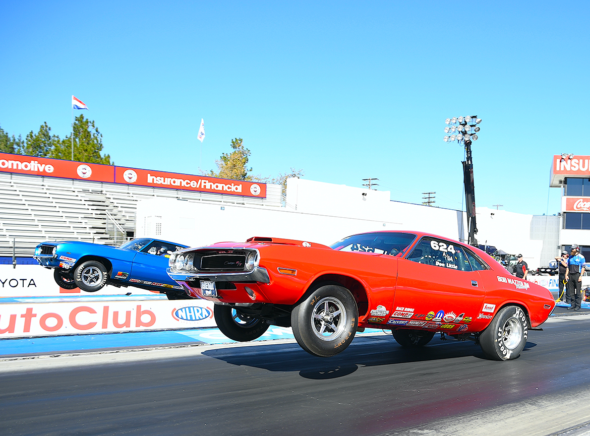 Two vehicles on a drag strip doing wheelies