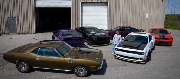 man standing in the middle of 6 Dodge vehicles