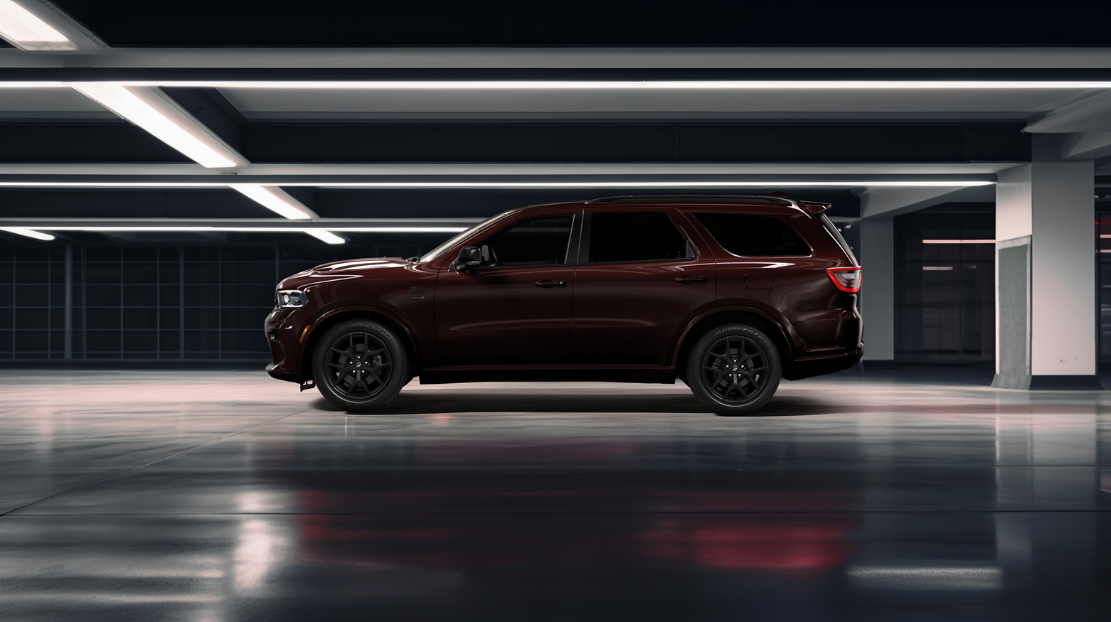 A dark red durango is parked in a modern, empty parking garage with glossy floors and bright overhead lighting, viewed from the side.
