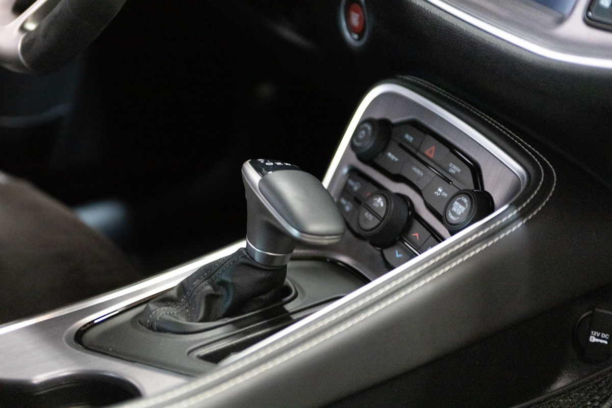 Close-up of a cars center console showing an automatic gear shift lever, climate control buttons, and part of the dashboard with a push-to-start ignition button.